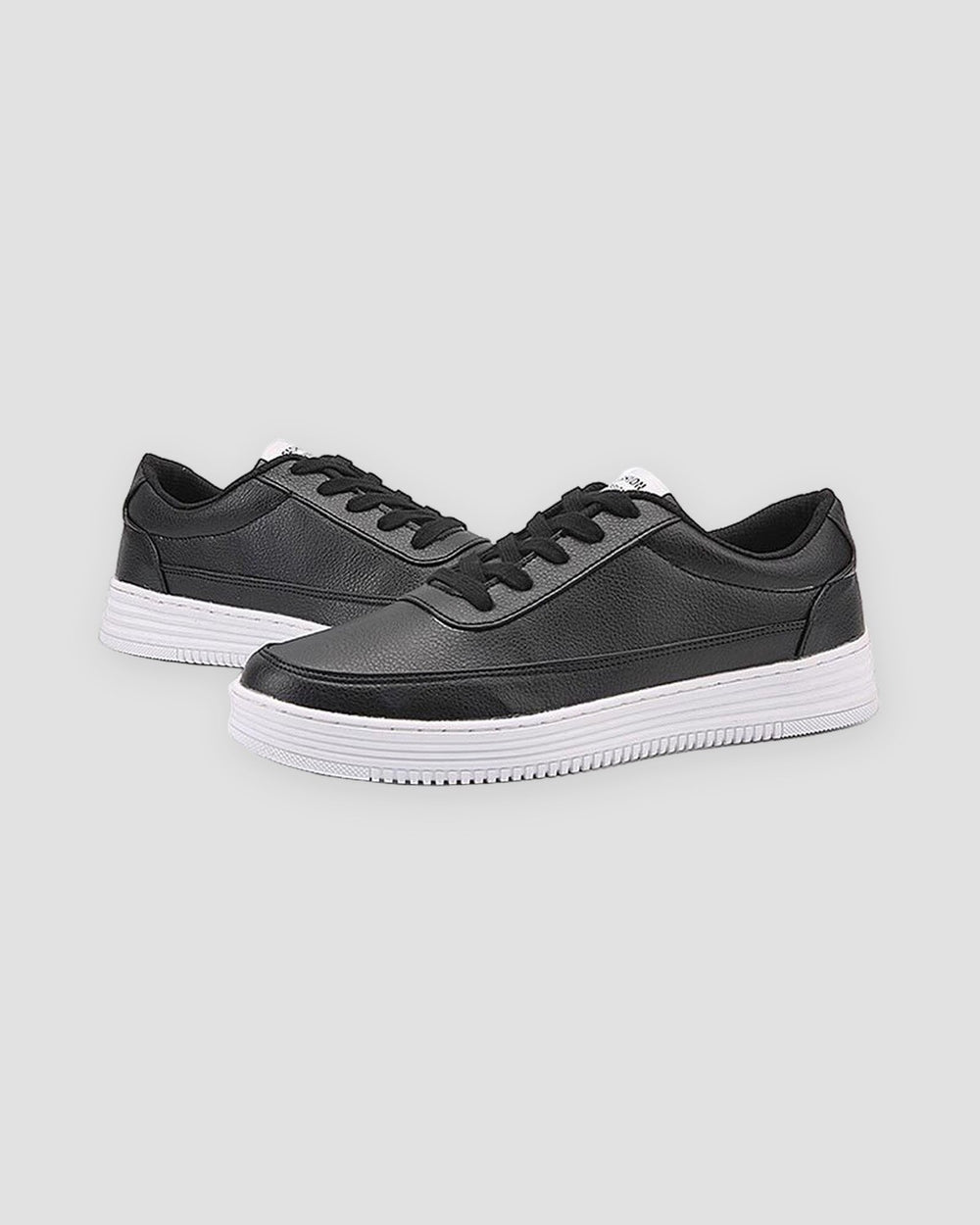Pair of black low-top platform sneakers with a thick ridged white sole, three-quarter view