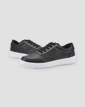 Pair of black low-top platform sneakers with a thick ridged white sole, three-quarter view