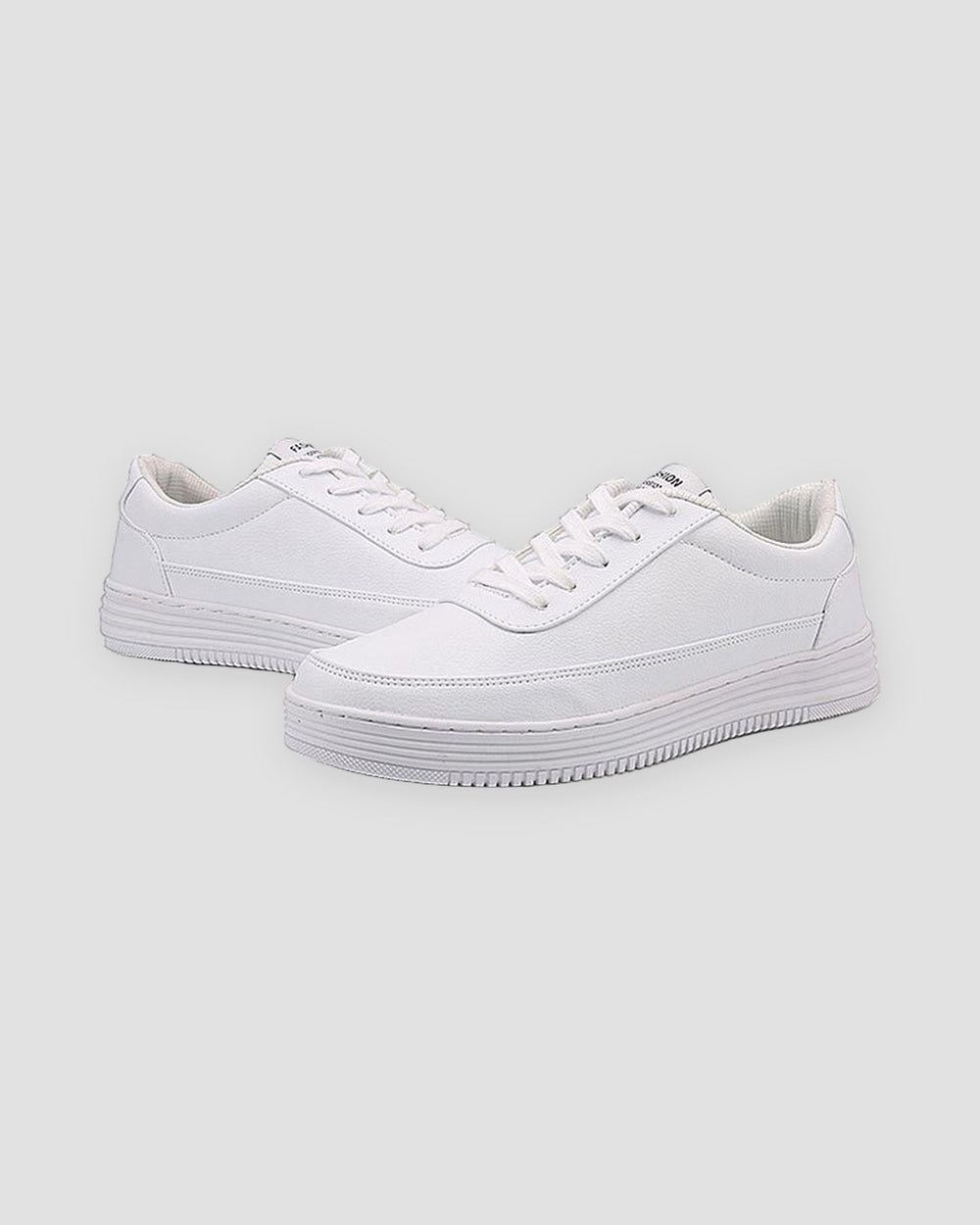 Pair of white low-top platform sneakers with a thick ridged white sole, three-quarter view