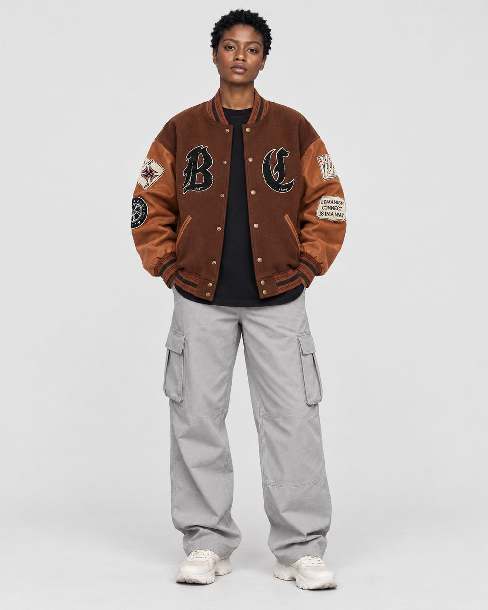 Model wearing the brown playing card patch varsity jacket, front view with B and C letters