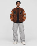 Model wearing the brown playing card patch varsity jacket, front view with B and C letters