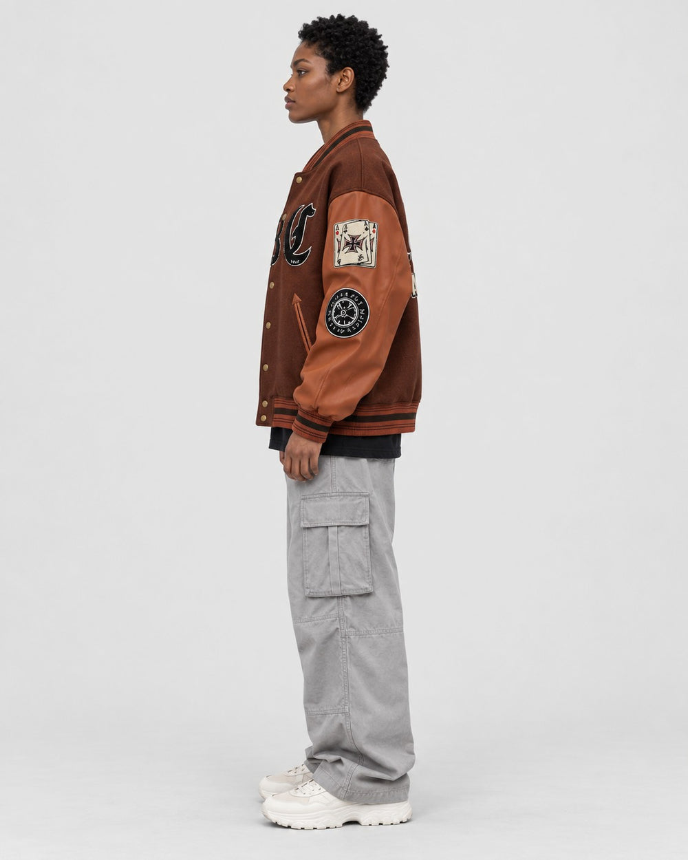 Model wearing the brown playing card patch varsity jacket, side view