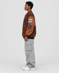 Model wearing the brown playing card patch varsity jacket, side view