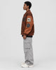 Model wearing the brown playing card patch varsity jacket, side view