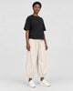 Model wearing the cream pleated corduroy pants with a black tee, three-quarter view