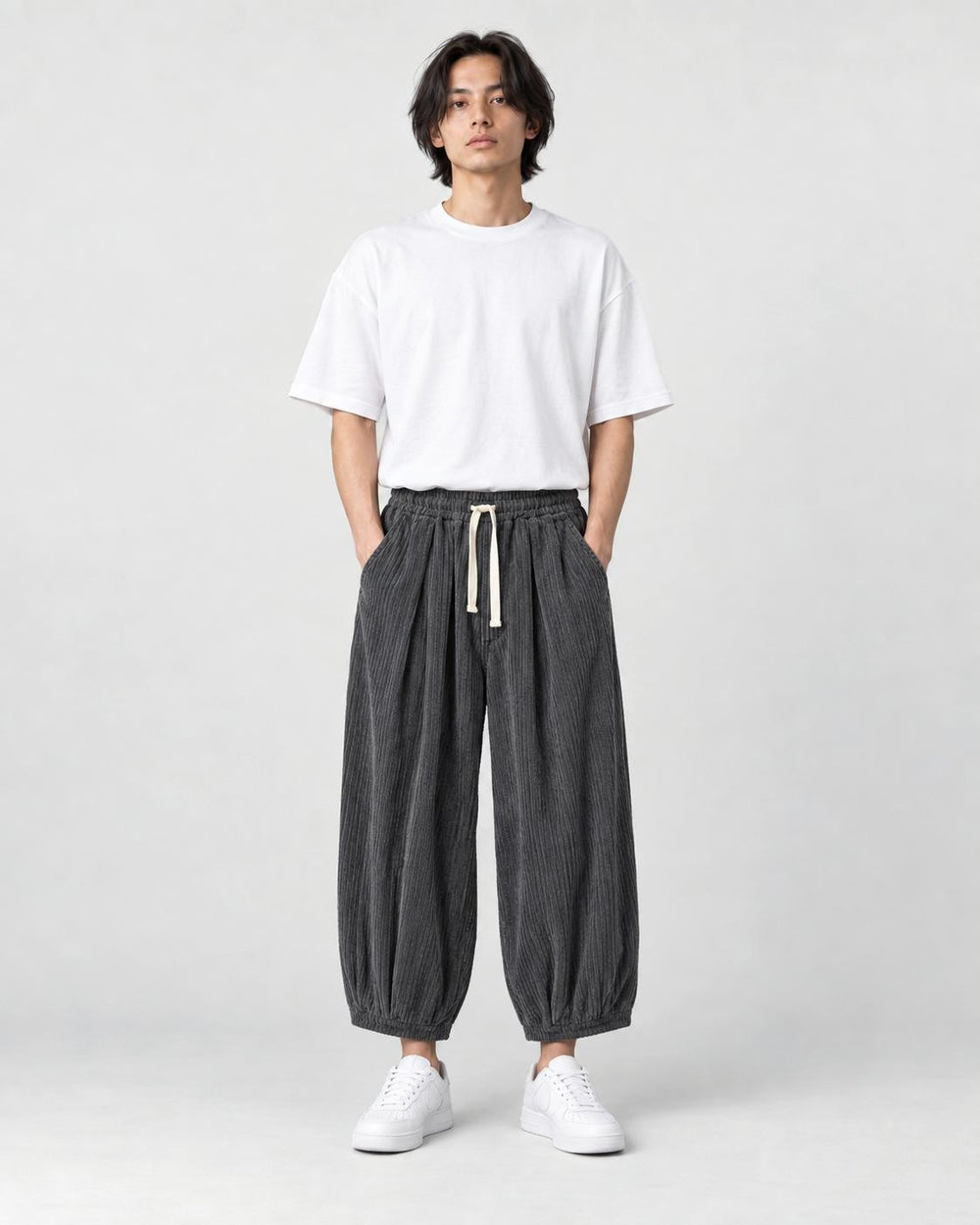 Model wearing the gray pleated corduroy wide-leg pants with a white tee, front view