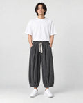 Model wearing the gray pleated corduroy wide-leg pants with a white tee, front view