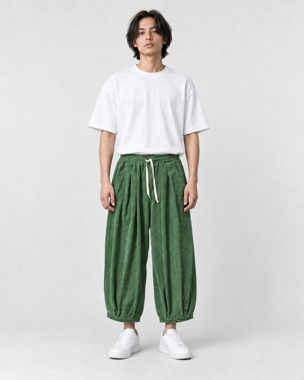 Model wearing the green corduroy wide-leg pants with a white tee, front view