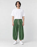 Model wearing the green corduroy wide-leg pants with a white tee, front view