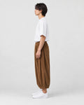 Model wearing the brown corduroy wide-leg pants, side view of the gathered hem