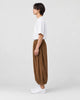 Model wearing the brown corduroy wide-leg pants, side view of the gathered hem