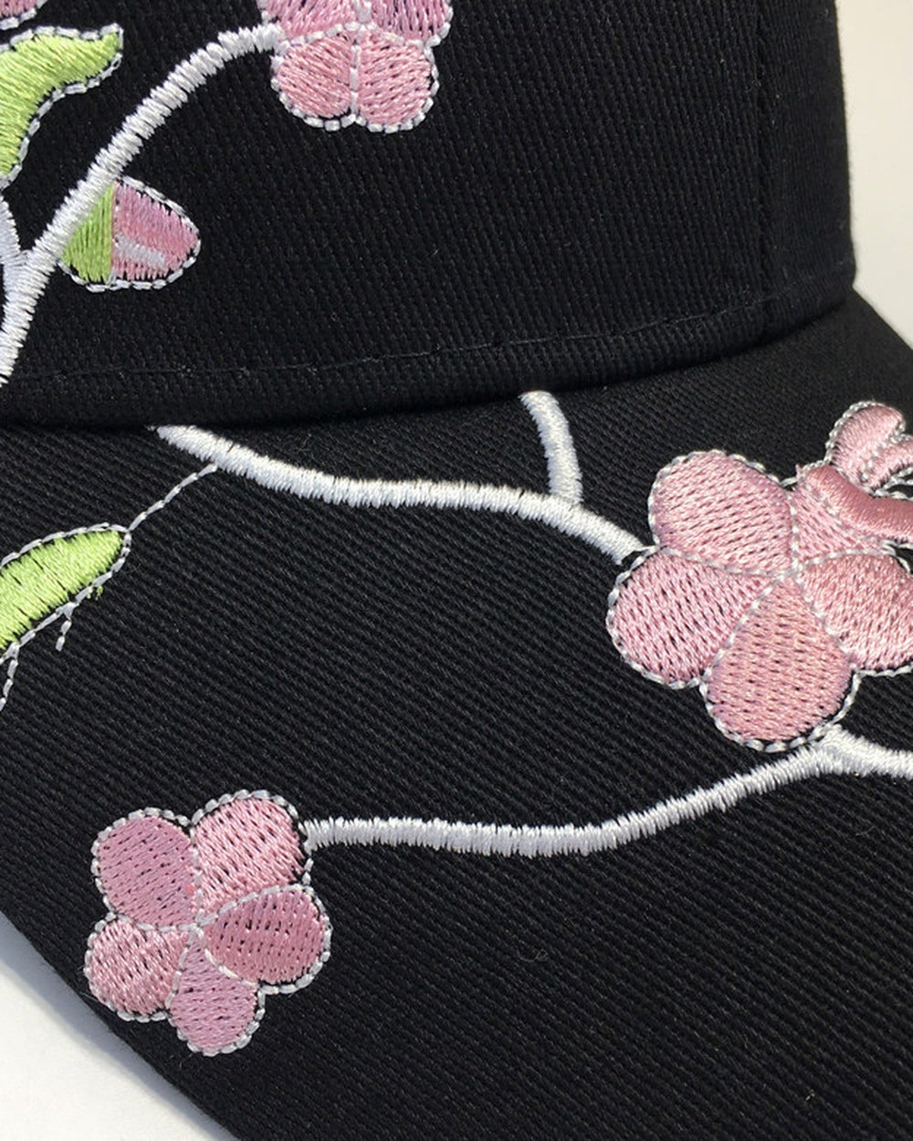 Close-up of the pink plum blossoms and green leaves embroidered on the brim