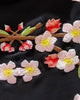 Close-up of the pink plum blossom embroidery across the black shirt's back