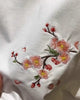 Close-up of the embroidered blossom sprig on the white shirt