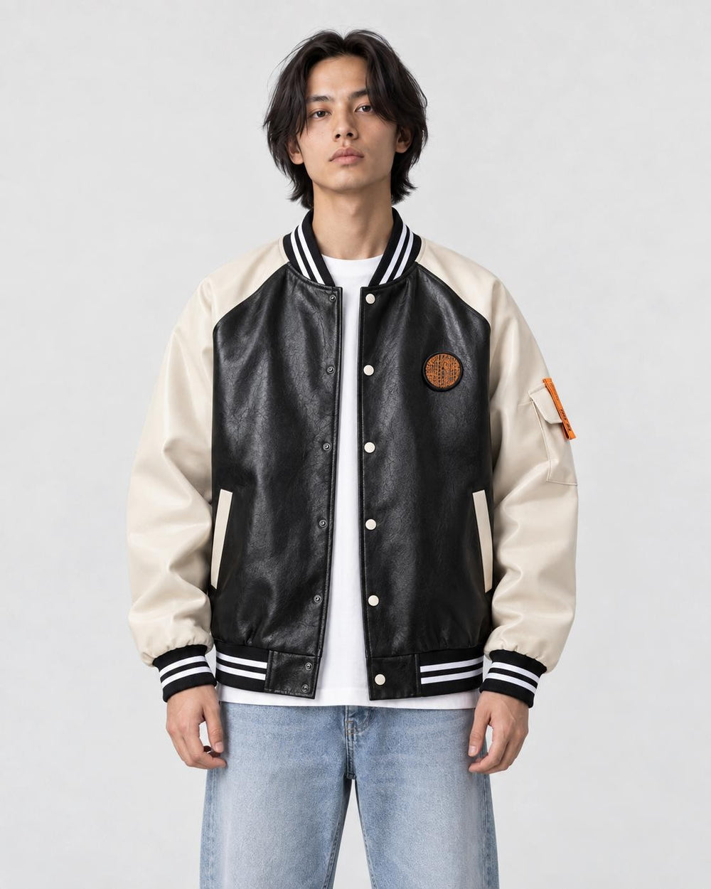 Model wearing the black and cream PU leather baseball jacket with a white tee, front view