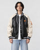 Model wearing the black and cream PU leather baseball jacket with a white tee, front view