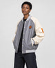 Model wearing the gray and cream PU leather baseball jacket with a black tee, three-quarter view