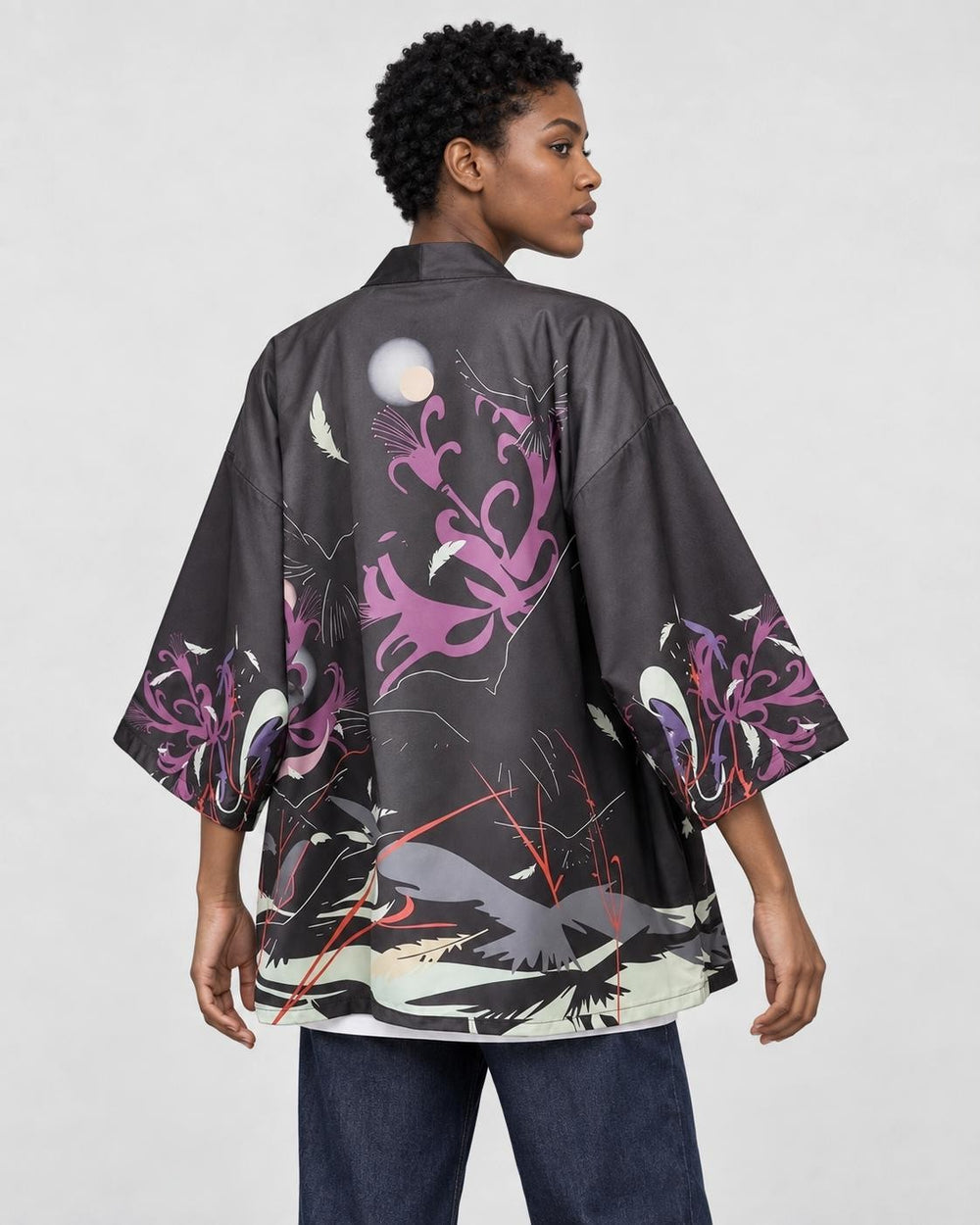 Model wearing the raven haori cardigan open over a white tee, back three-quarter view