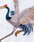 Close-up of the embroidered red-crowned crane in cream, tan, teal and navy thread