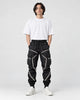 Model wearing black cargo joggers with silver reflective tape lines, a white tee and chunky sneakers, front view