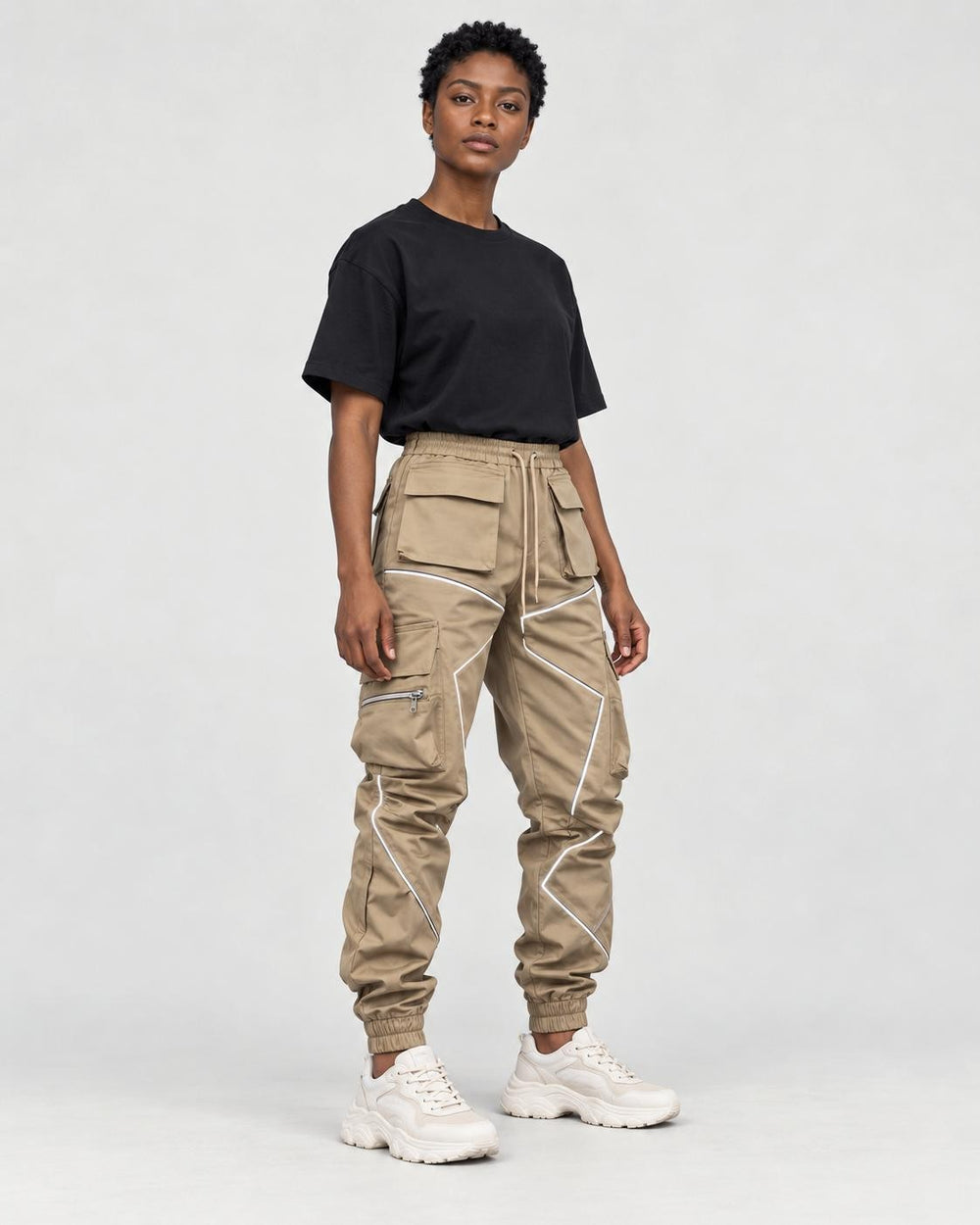 Model wearing khaki cargo joggers with reflective tape lines and a black tee, three-quarter view