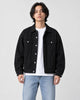 Model wearing the black denim trucker jacket open over a white tee, front view