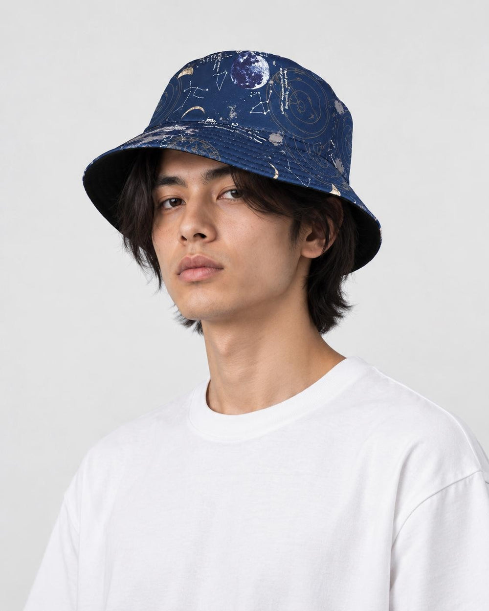 Model wearing the navy astronaut and star chart bucket hat with a white tee, three-quarter view