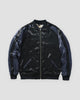 Plain reverse side of the jacket in glossy black with navy raglan sleeves and a silver zip