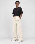 Model wearing cream ribbed corduroy wide-leg pants with a black tee and white sneakers, three-quarter view