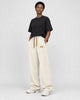 Model wearing cream ribbed corduroy wide-leg pants with a black tee and white sneakers, three-quarter view