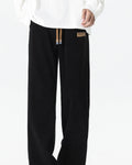 Black ribbed corduroy wide-leg pants with a tan drawcord, worn with a white sweatshirt