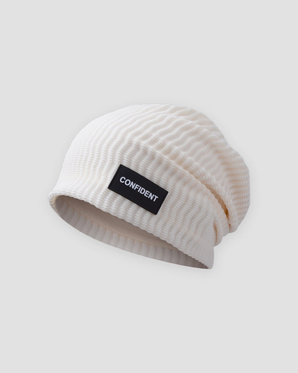 White ribbed slouchy beanie with a small black label reading CONFIDENT