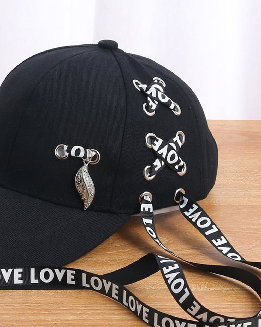 Close-up of the LOVE ribbon lacing and the silver leaf pendant on the black cap