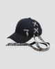 Black baseball cap laced with LOVE ribbon and a silver leaf pendant, three-quarter view