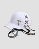 White baseball cap laced with LOVE ribbon and a silver leaf pendant, three-quarter view
