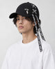 Model wearing the black ribbon-laced cap with a white tee, three-quarter view