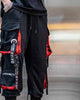 Close-up of the printed ribbon straps, metal ring and red camo pocket lining on the joggers