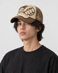 Model wearing the beige and brown fist patch cap, three-quarter view