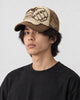Model wearing the beige and brown fist patch cap, three-quarter view