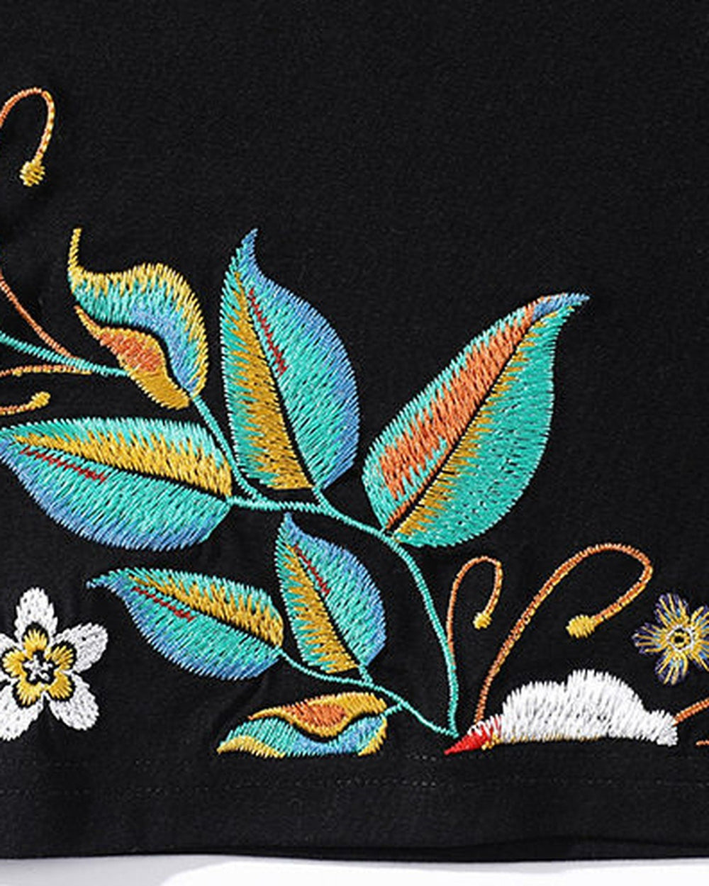 Close-up of the teal and gold leaves and white blossom embroidered near the hem