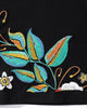 Close-up of the teal and gold leaves and white blossom embroidered near the hem
