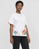 Model wearing the white rose hem embroidered tee with black jeans, three-quarter view
