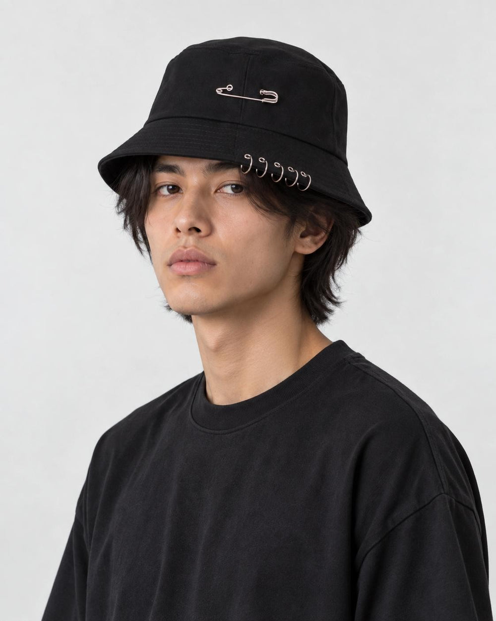 Model wearing the black safety pin bucket hat, three-quarter view