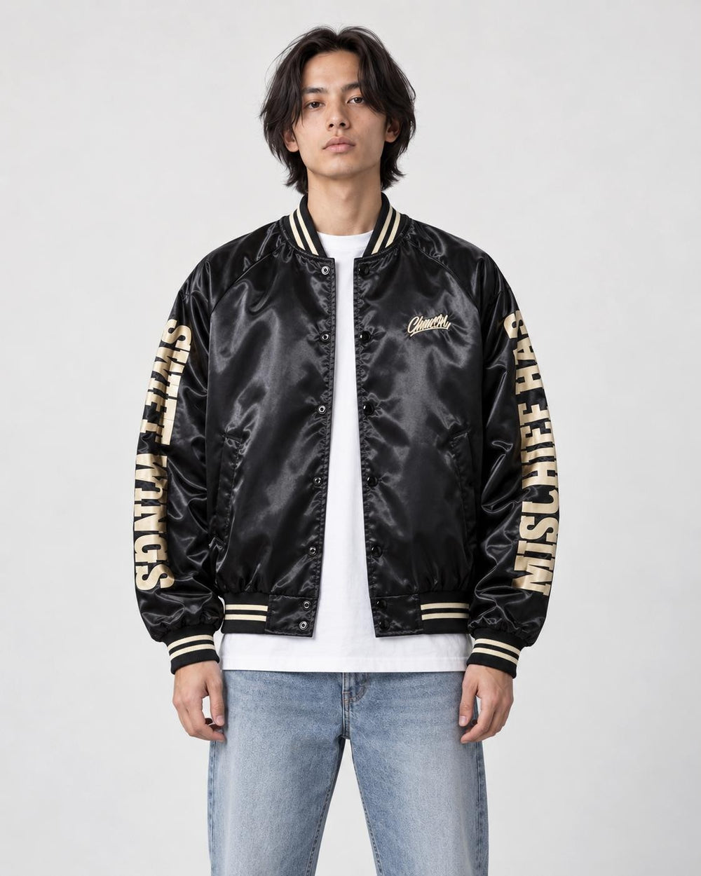 Model wearing the black bomber jacket with cream sleeve lettering over a white tee, front view