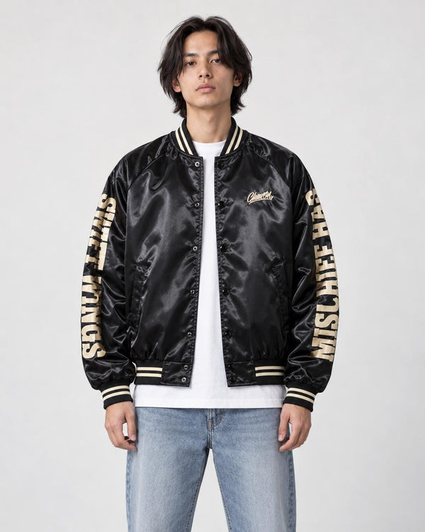 Model wearing the black bomber jacket with cream sleeve lettering over a white tee, front view