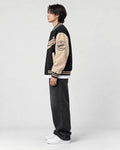 Model wearing the black script letter varsity jacket, side view of the sleeve badge