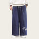 Person wearing navy blue pants with white embroidery