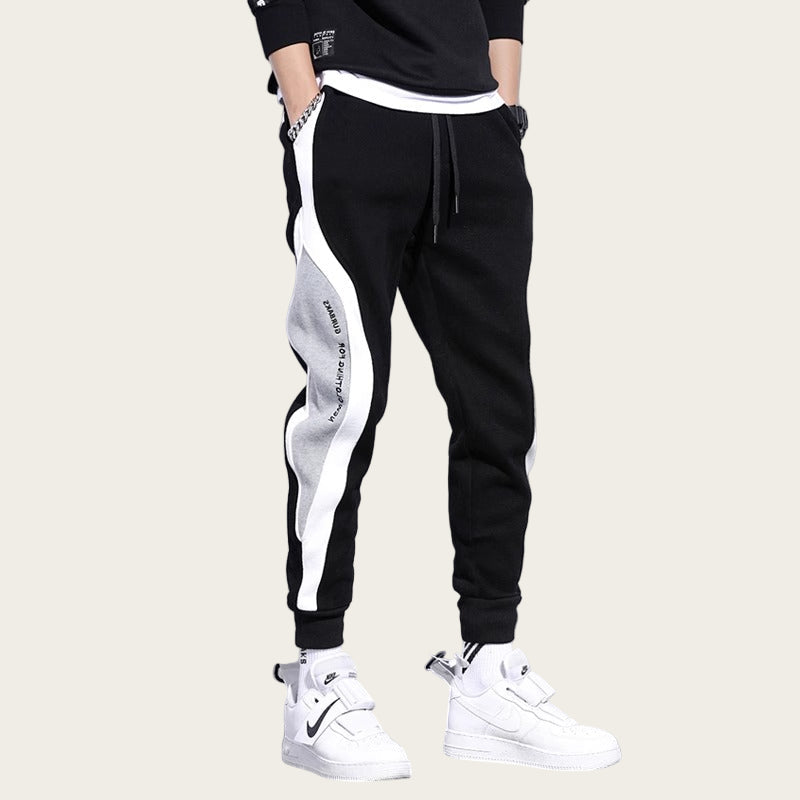 Black and white jogger pants with flame graphic and text on a gray background