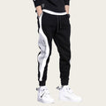 Black and white jogger pants with flame graphic and text on a gray background