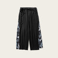 Black pants with floral side panels on a white background